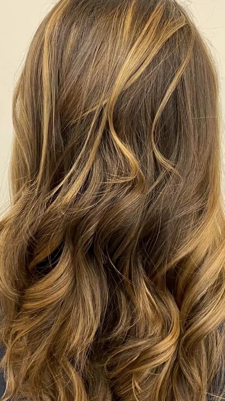 Cabelo com mechas loiras e cor de caramelo em ondas soltas, trabalho do salão